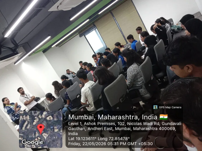 Young people seated in rows of chairs in a training hall while two facilitators address them