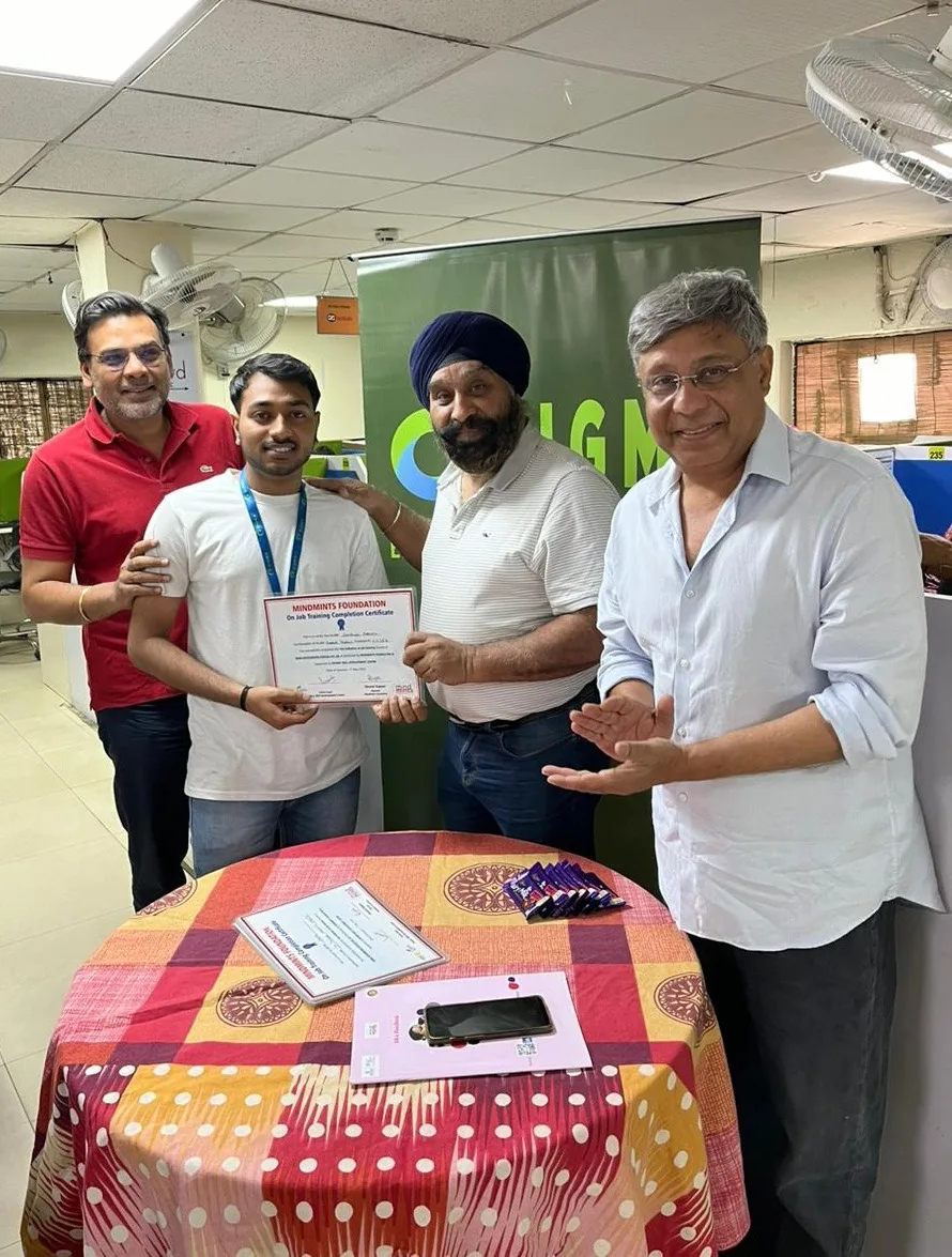 A trainee receiving a MindMints Foundation on-the-job training completion certificate at a partner workplace