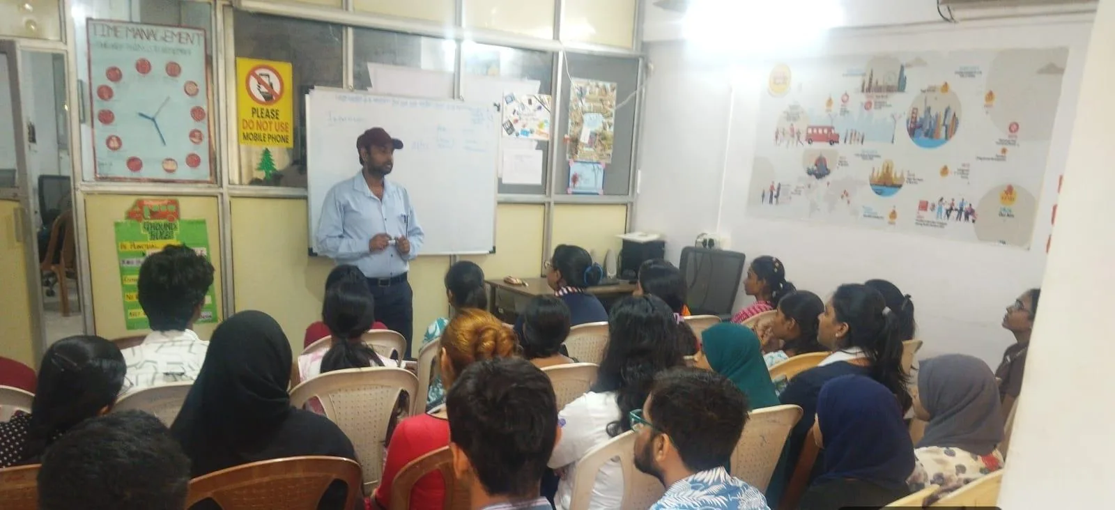 Trainer at a whiteboard addressing a full classroom of students at the Mira Road centre